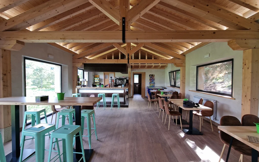 interior de cafetería de madera con mesas bajas y altas y tejado a dos aguas
